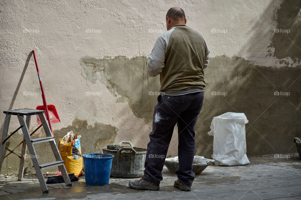 Hombre arreglando los muros de una casa antigua del barrio de Gracia. 