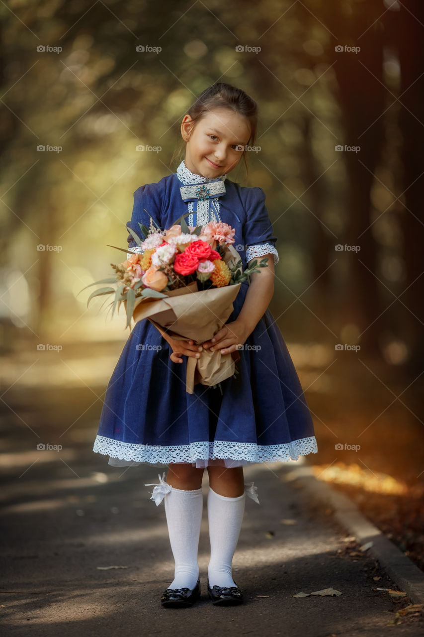 Little schoolgirl with a bouquet at a park 