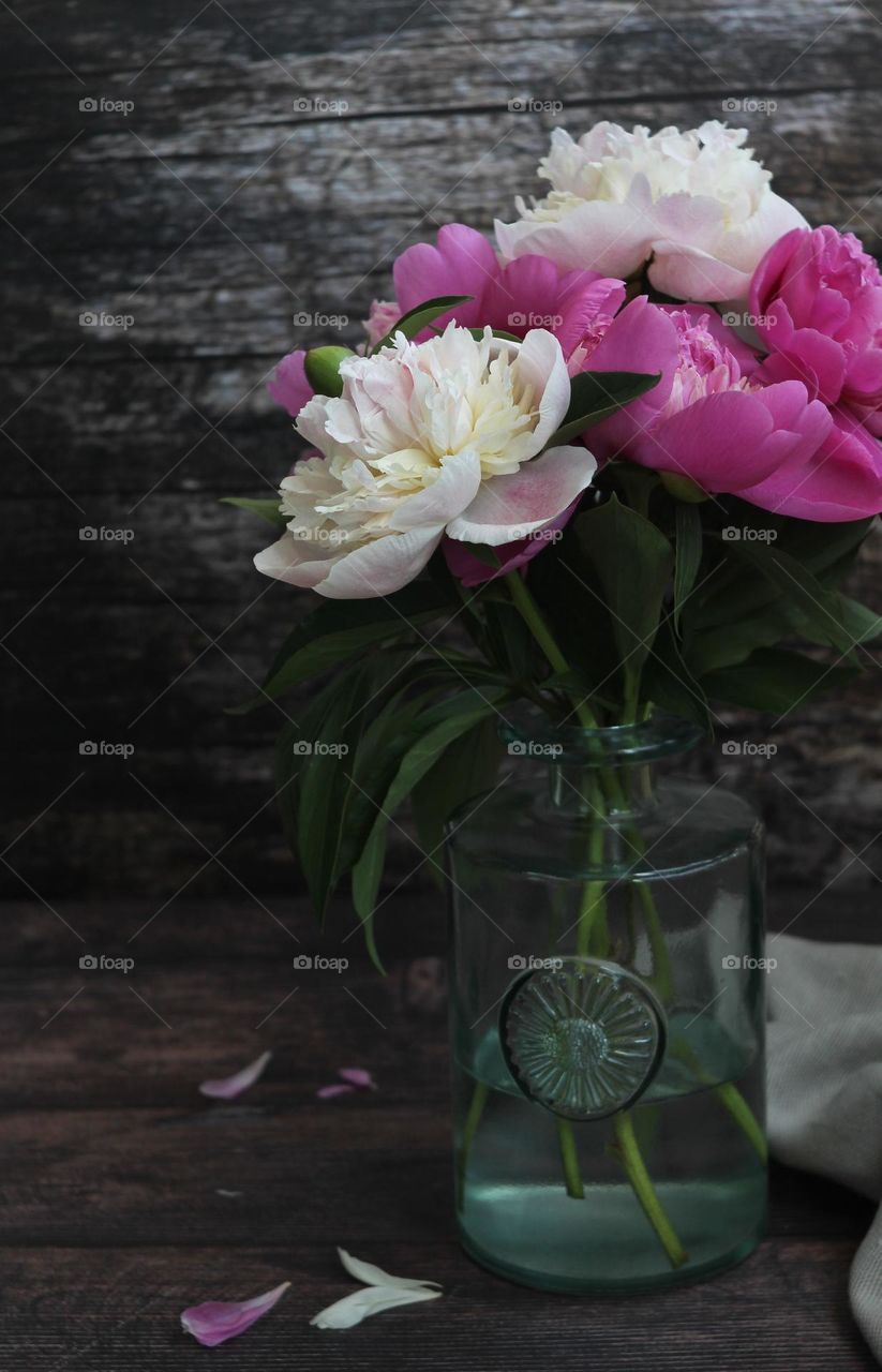 A bouquet of peonies in a transparent vase