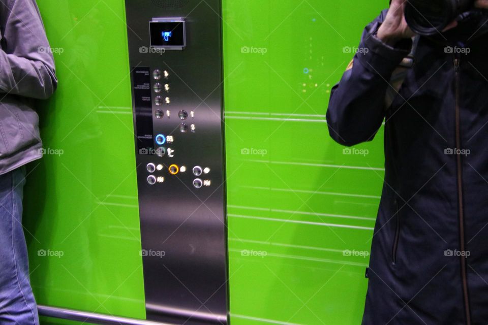Reflection of two people in the mirror of a green elevator