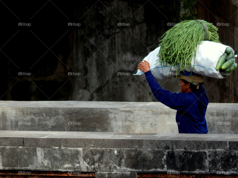 a women carries a heavy burden on her head