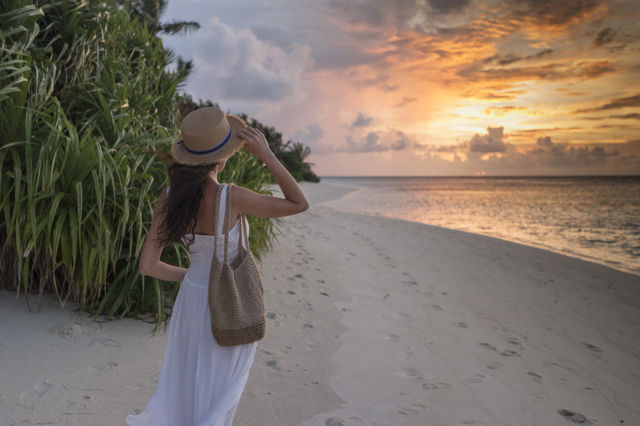 Girl in white dress and hat looking at the sunset