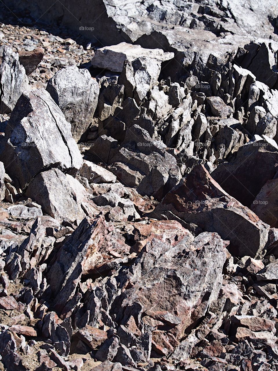 Jagged rocks and boulders along the shoreline of Ochoco Lake in Central Oregon on a sunny spring day.