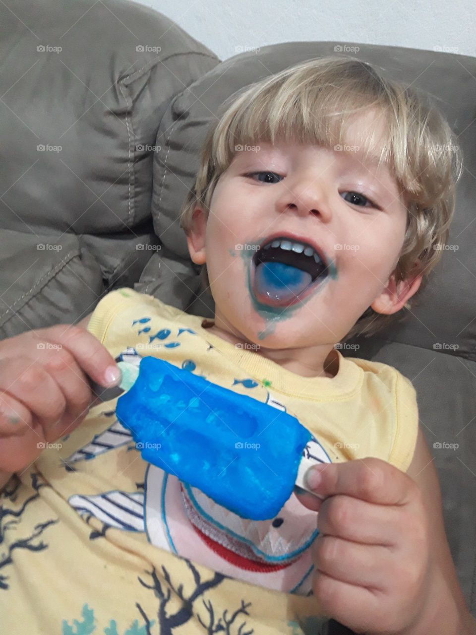 child sucking a blue popsicle happy