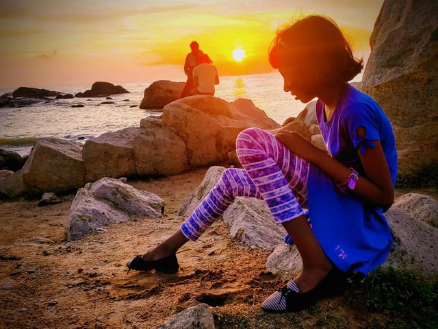 A little girl sitting on the beach side during sunset in the evening