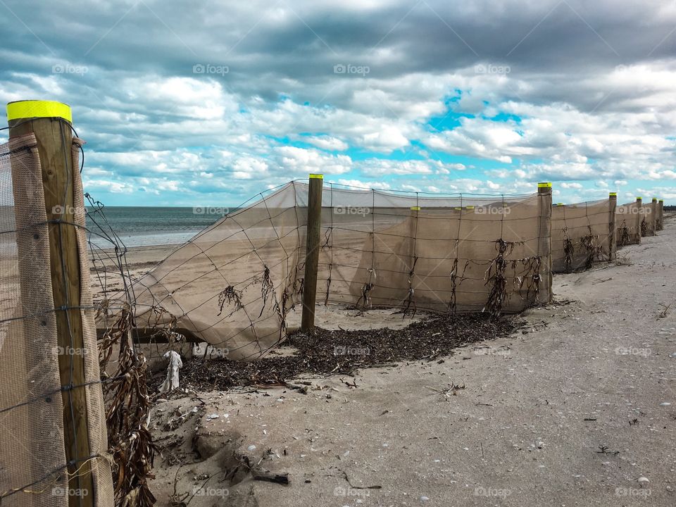 Weathered sand barrier fence on remote beach on windy day in south Australia 