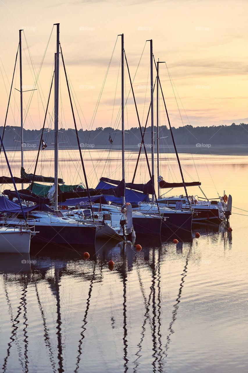 Yachts and boats moored in a harbour at sunrise. Candid people, real moments, authentic situations