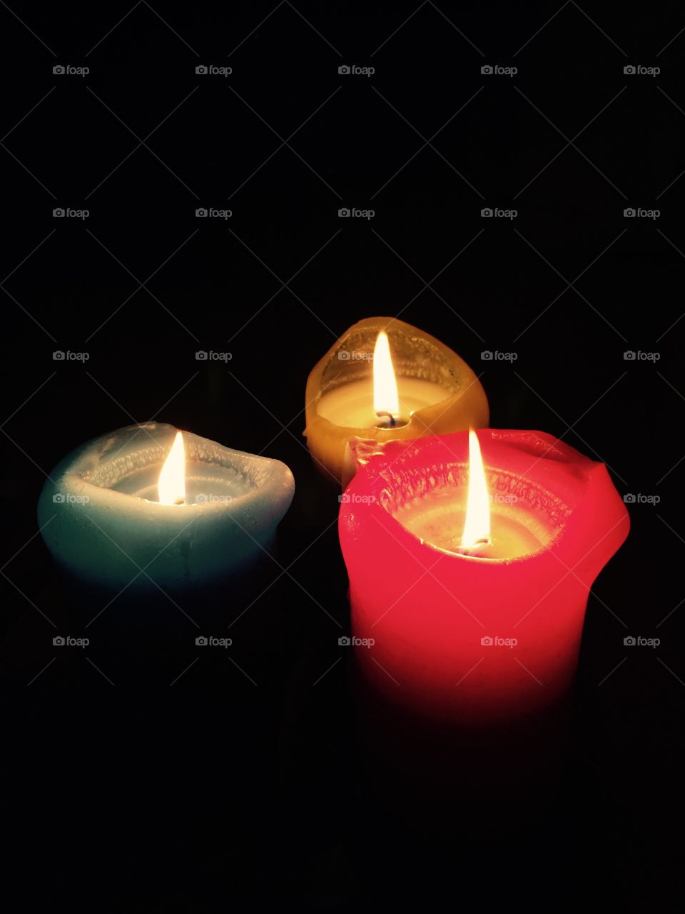 Three colours. Thick coloured burning candles in the dark