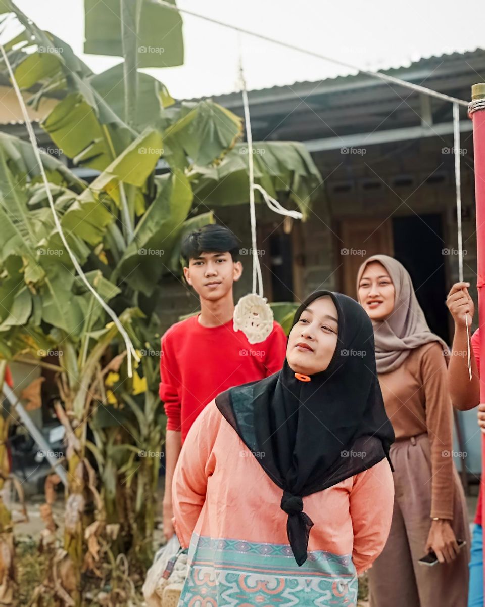 Portrait of young mothers having a cracker eating competition on Indonesian independence day witnessed by residents