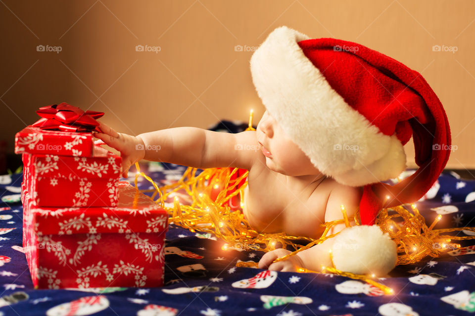 Baby wrapped with light holding gift boxes