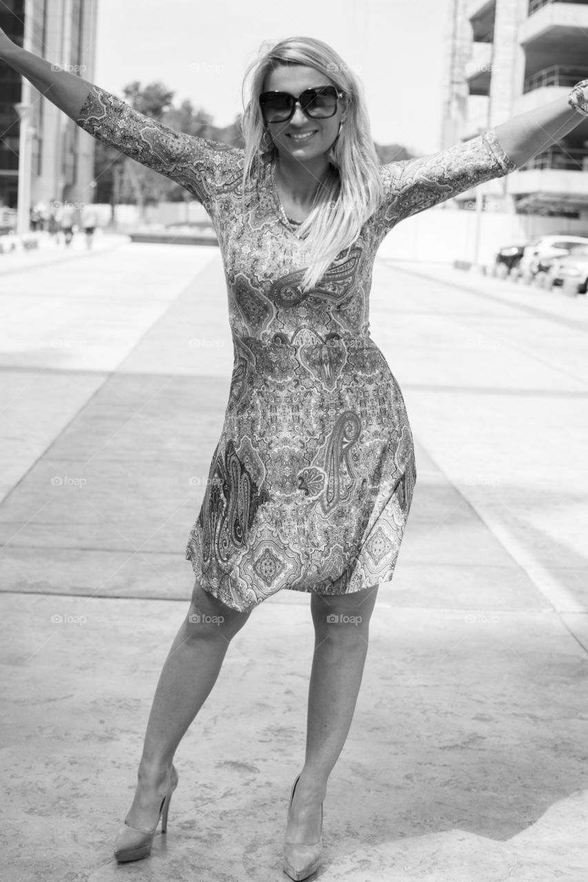 Happy woman standing on street wearing sunglasses