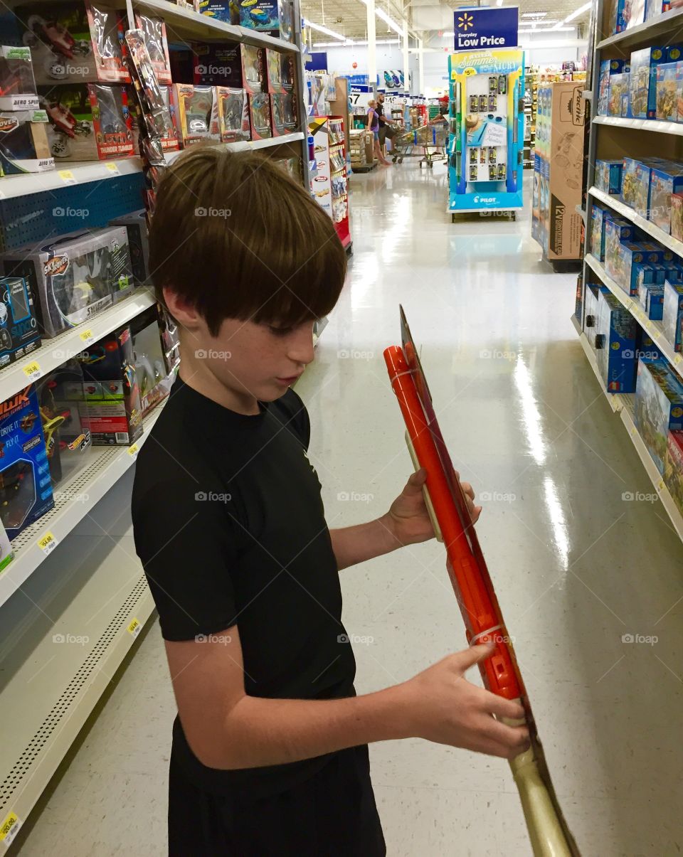 Young boy shopping in a store looking at a toy.