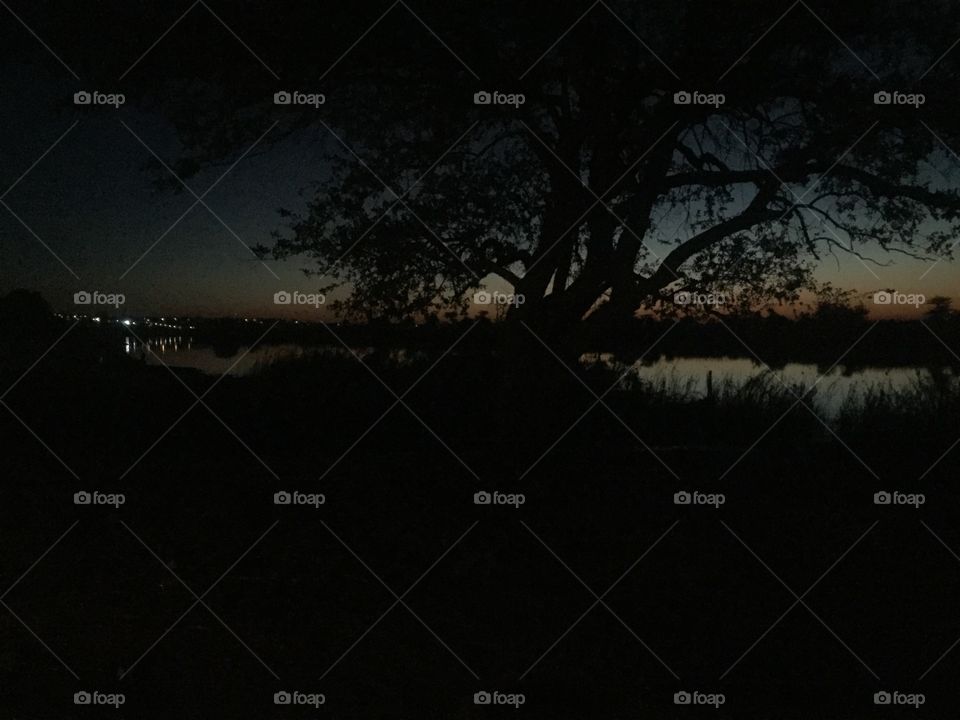 A picture of the river water reflecting the sky at sunset and city lights. 