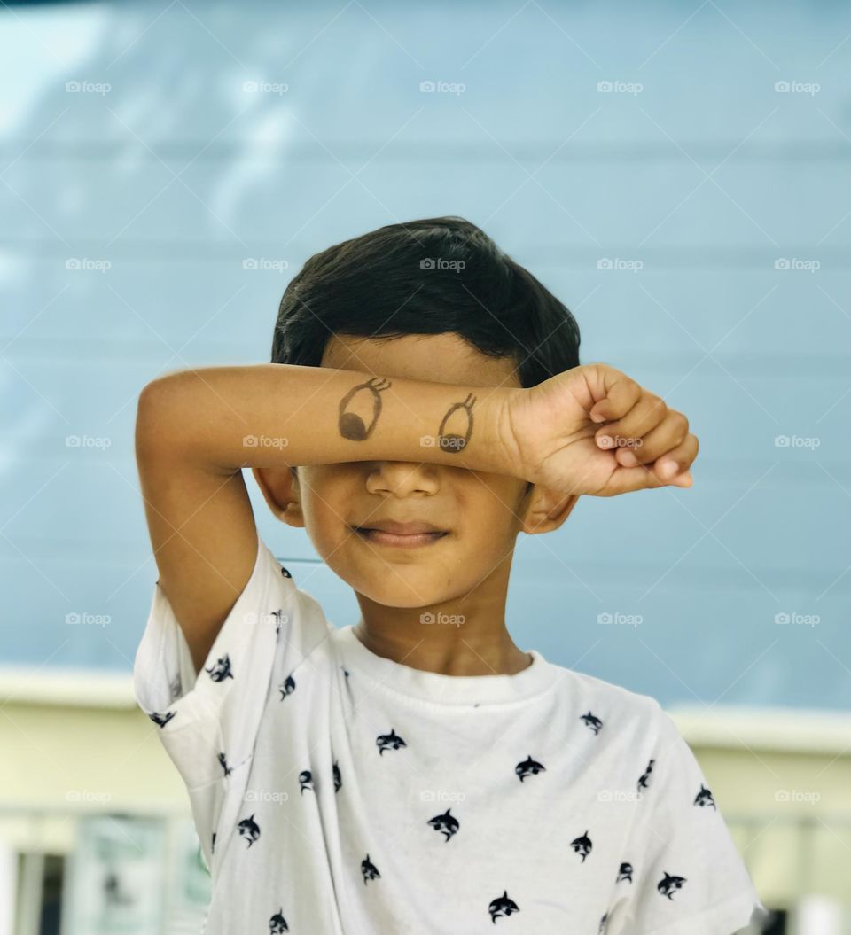 Fun with kids.cute boy made cartoon eyes on his hand and cover his eyes to make fun.