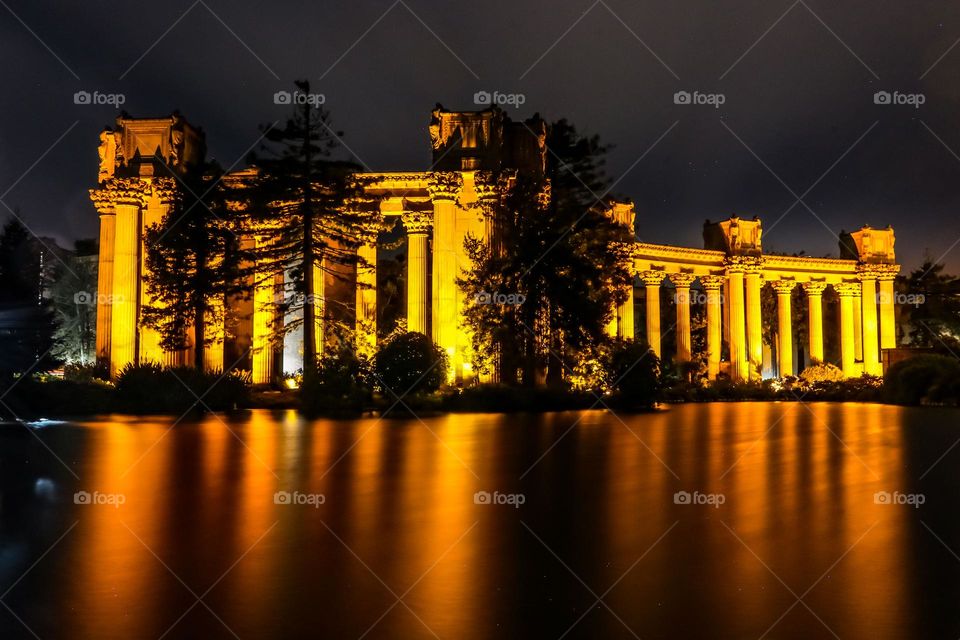 Palace of Fine Arts in San Francisco California at night reflecting the lights of this landmark structure on a calm evening in the lagoon with the faint stars of the night sky