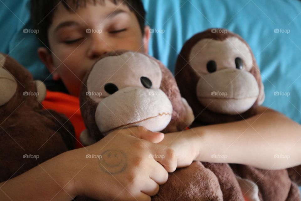 Child sleeping white holding his stuffed animals 