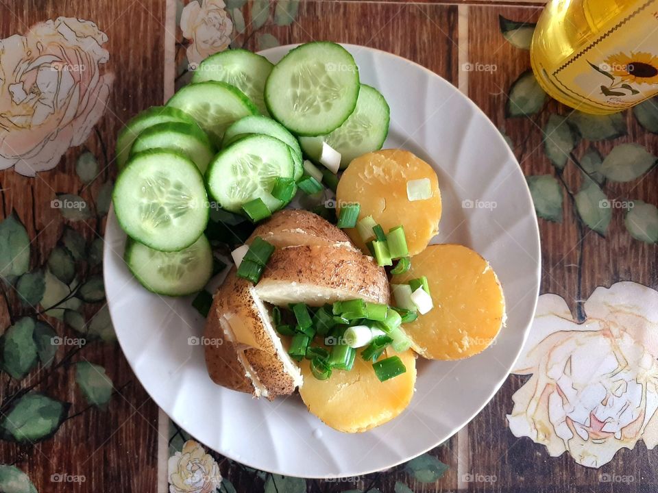 на 
 тарелке варенный картофель зеленый лук и огурец