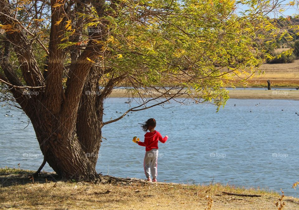 the girl in a red jacket by the lake