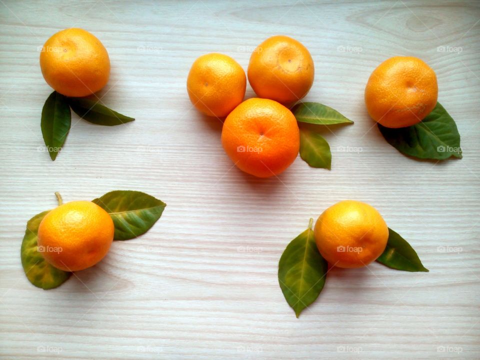 tangerines and grern leaves on a light wooden background