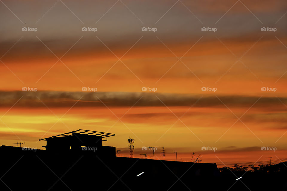 Beautiful light of Sunset with clouds in the sky reflection behind the building.