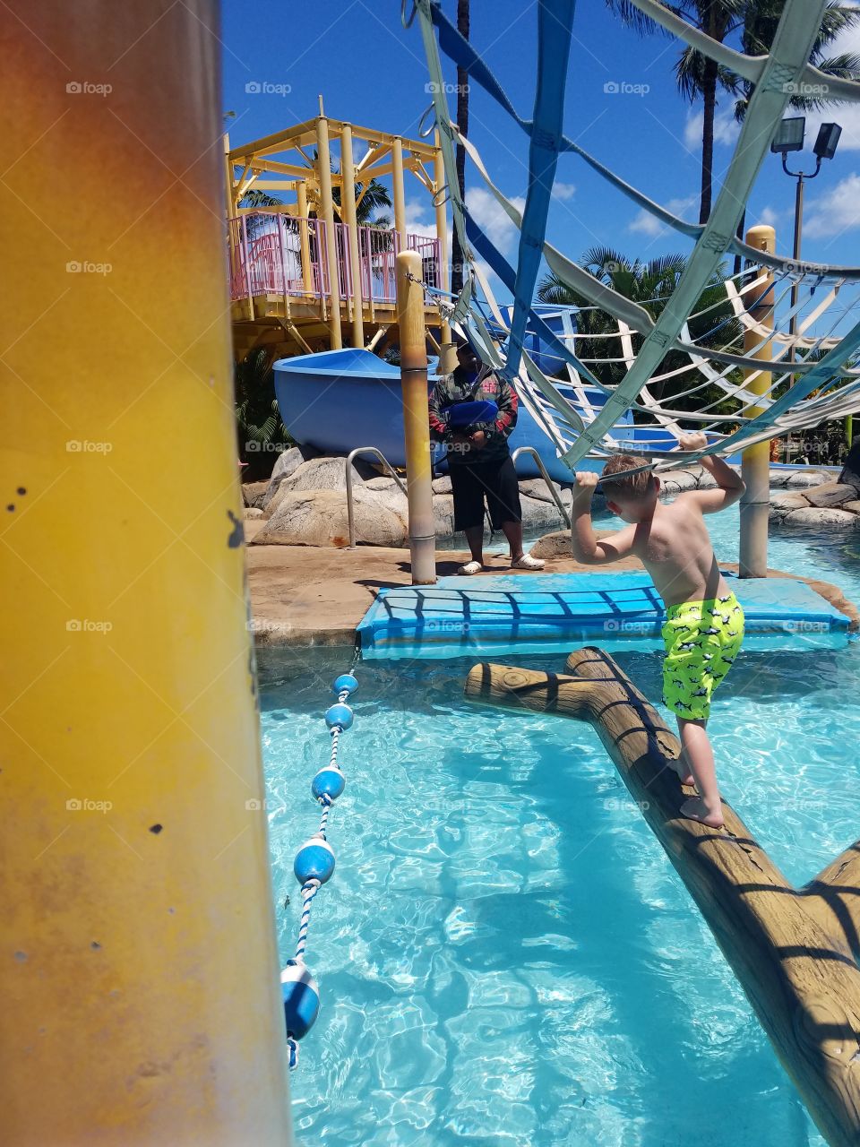 Boy crosses log in pool at Wet n Wild Oahu