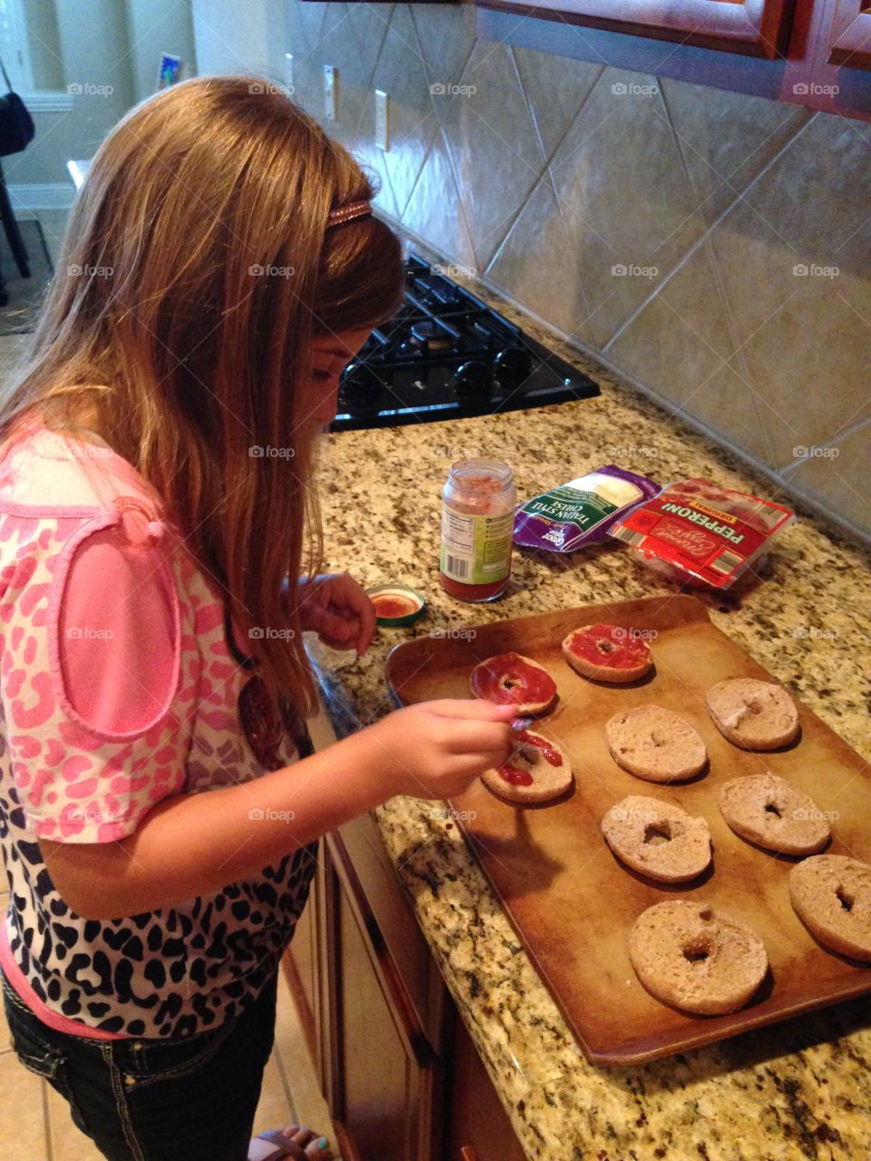 Lunch time!. Girl making bagel pizzas