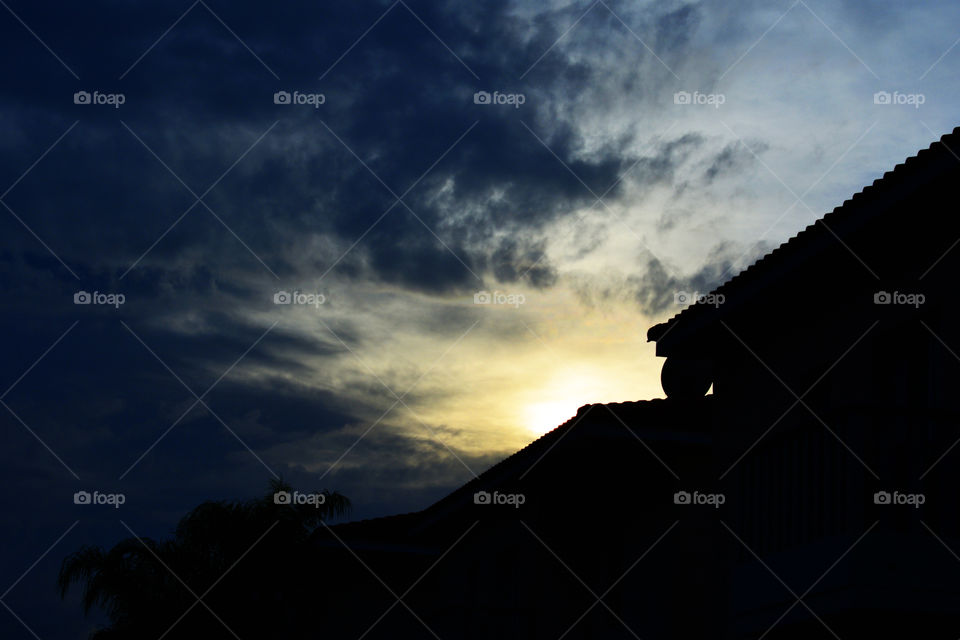 Silhouette photo of sunset with cloudy sky beside the houses