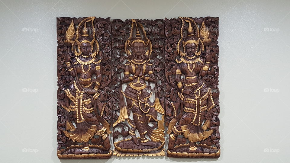 sculpture of 3 dancing ladies made of wood with gold accents and lace design