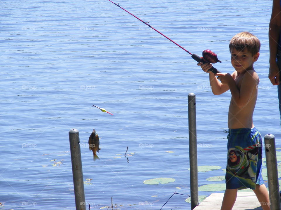 This boy caught a fish in the lake.