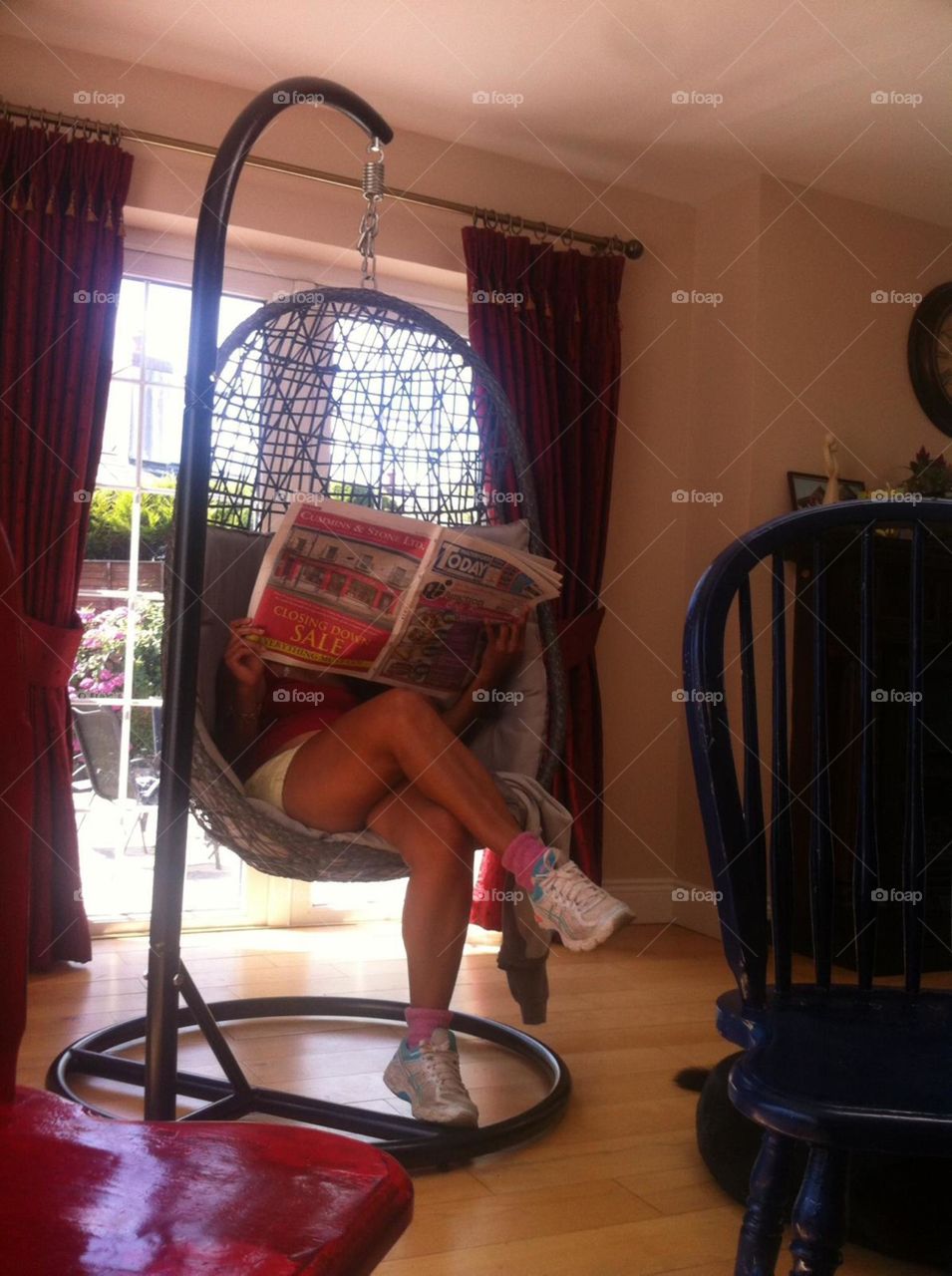 Just casually reading a newspaper on an eggshell chair.
