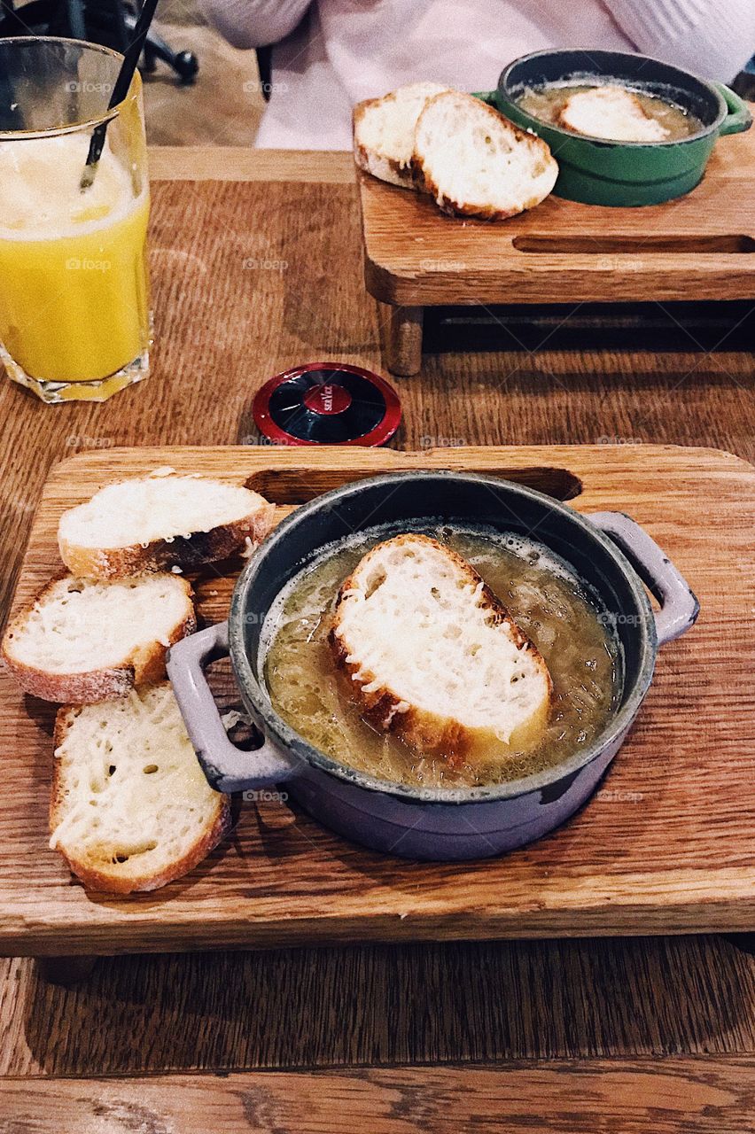 Dinner with french onion soup and bread on wood table 