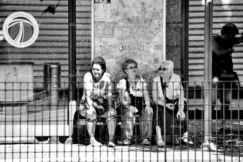 Three elderly women seated waiting for the bus