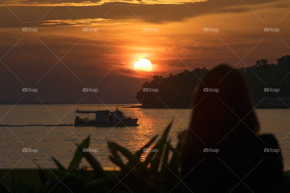 silhouette a girl watching boat against sunset