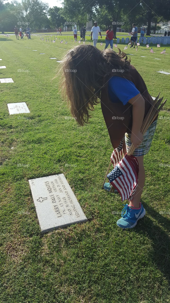 Girl Scout places flag on veterans' graves at Biloxi National Cemetery.