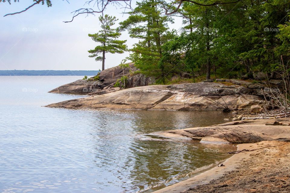 Rustic beach, pine trees and Canadian Shield on the shore at Killbear Provincial Park. Ontario, Canada