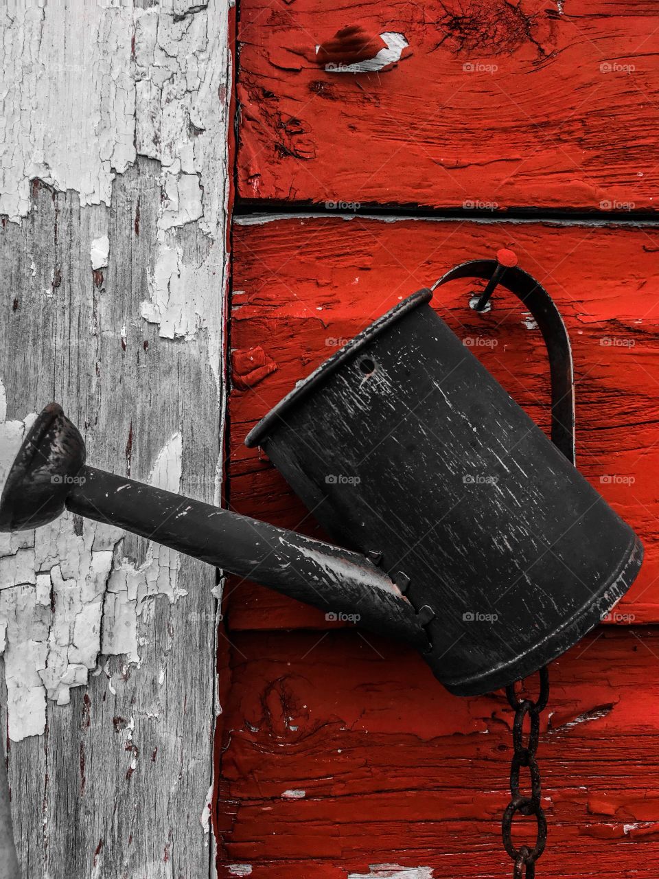 A rusty watering can on a flaking barn.