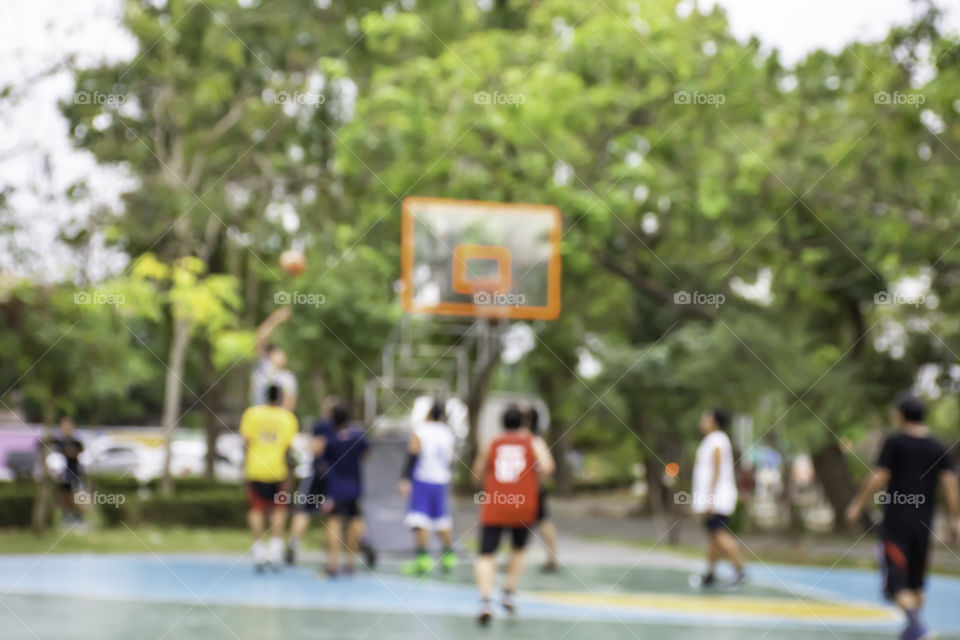 Blurry image of elderly men and teens playing basketball in the morning at BangYai Park , Nonthaburi in Thailand.