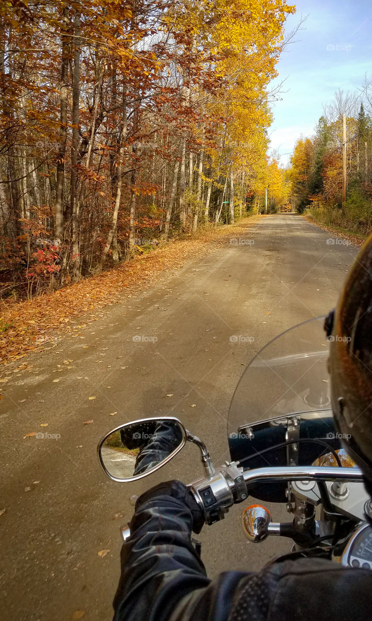 Motorcycle ride down a dirt road in Autumn from perspective of the rider.