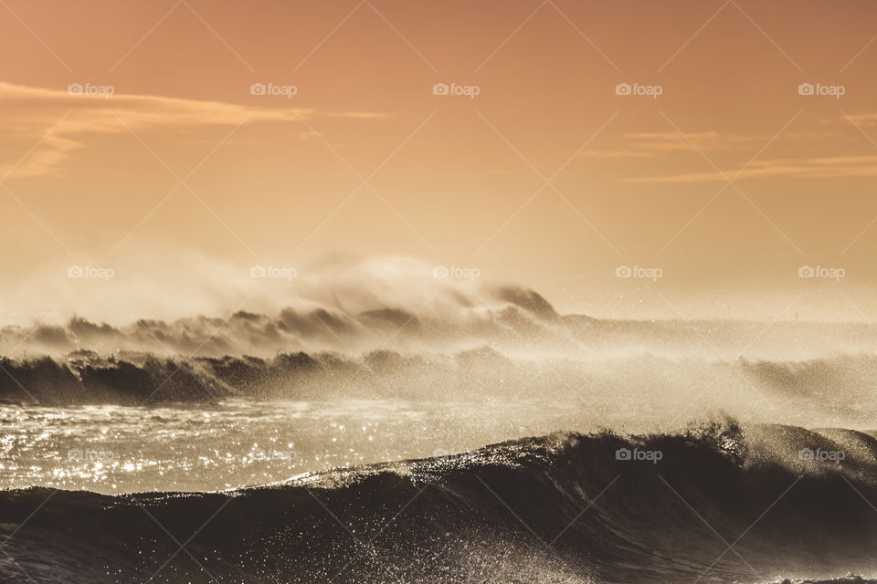 Heavy surf coming under the warm glow of the setting sun. 