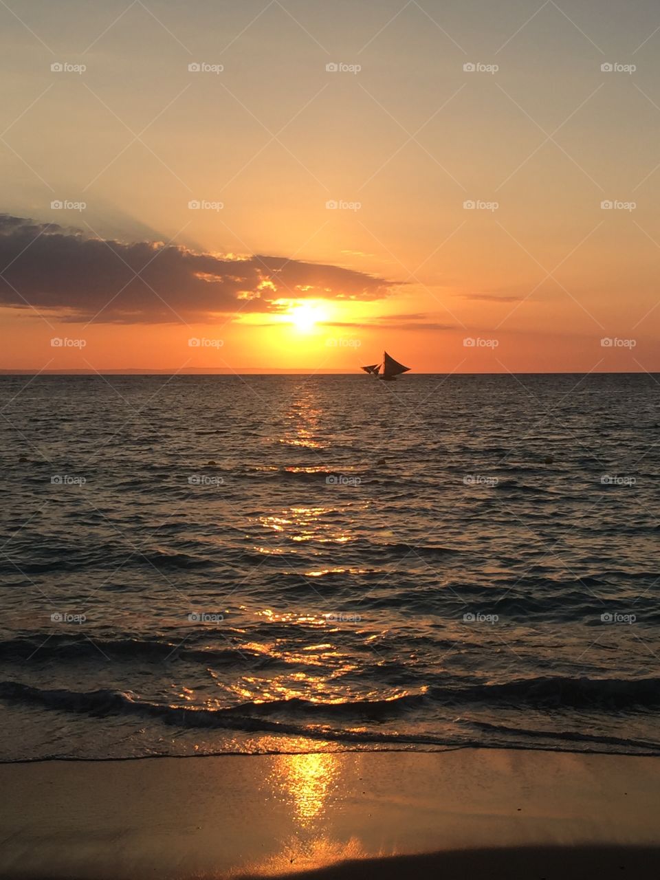 Beach sunset with a sailboat passing by...