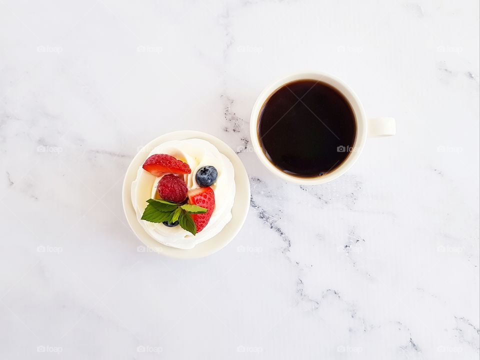Top view of cup with black coffee and fruit desserts.