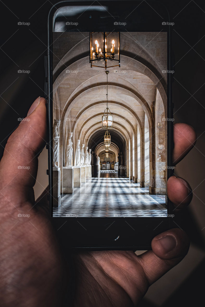 Versailles castle, and person holding phone