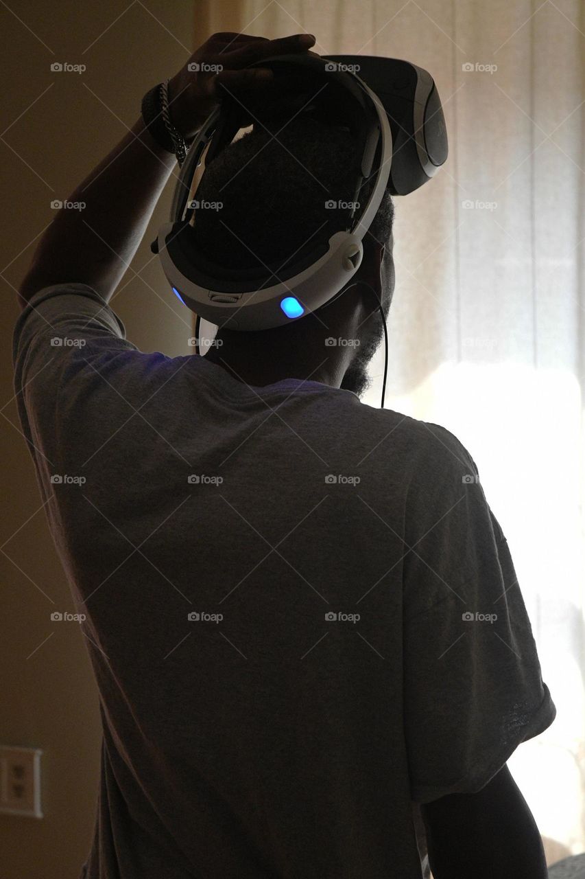 A young man engages in a session of virtual reality gaming in the living room of his home.