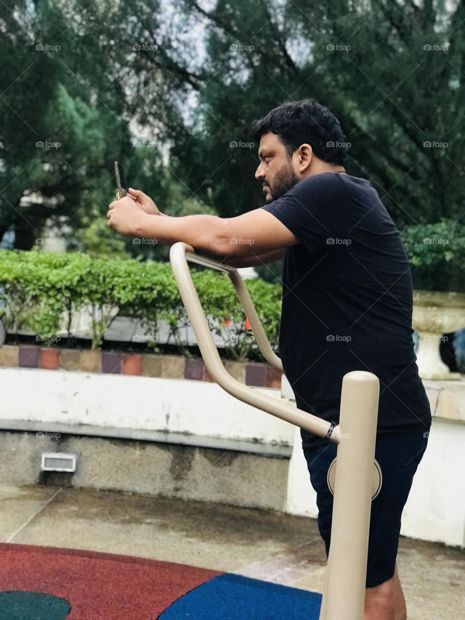 Man looking phone while doing exercise at outdoor gym