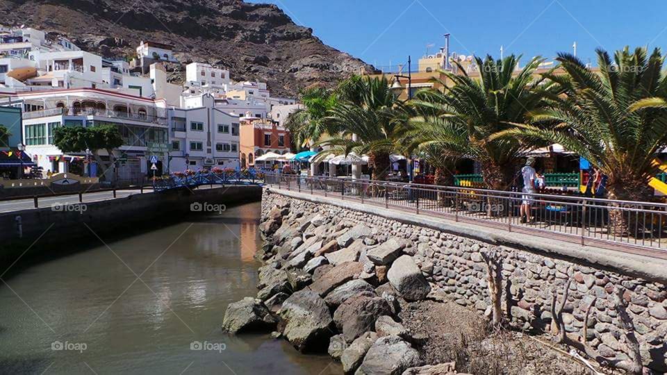Puerto de Morgan 
Gran Canaria 

Puerto de Mogán is a picturesque resort and fishing village in the municipality of Mogán, set at the mouth of a steep-sided valley on the southwest coast of the island of Gran Canaria. It attracts many tourists either to stay or on day-visits. Canals linking the marina to the fishing harbour have led to it being nicknamed "Little Venice" or the "Venice of the Canaries". Restaurants and bars fringe the marina and the beach front. On Fridays there is a very popular market which brings in tourists from all over the island.

Puerto de Mogán has very few buildings over two stories high, and the government of Gran Canaria restricts new buildings taller than this.

Puerto de Mogán can be reached via a new extension of the motorway GC1 (opened in March 2013) which