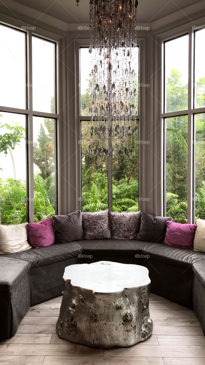 A cozy little place. Window, pillows, foliage, chandelier, genie bottle, design, designer, interior design, pretty, green, pink, sofa