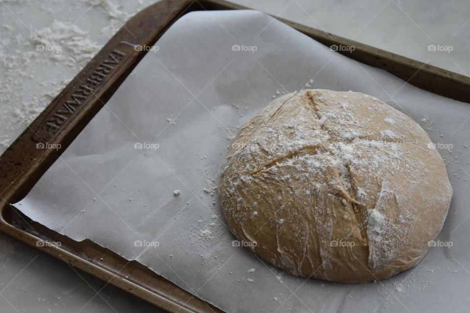 Irish soda bread dough sprinkled with flour on a parchment-lined baking sheet