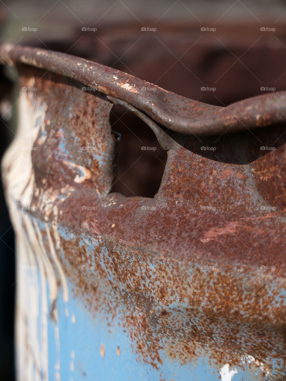 An old rusted oil barrel with a big hole in it closeup. 