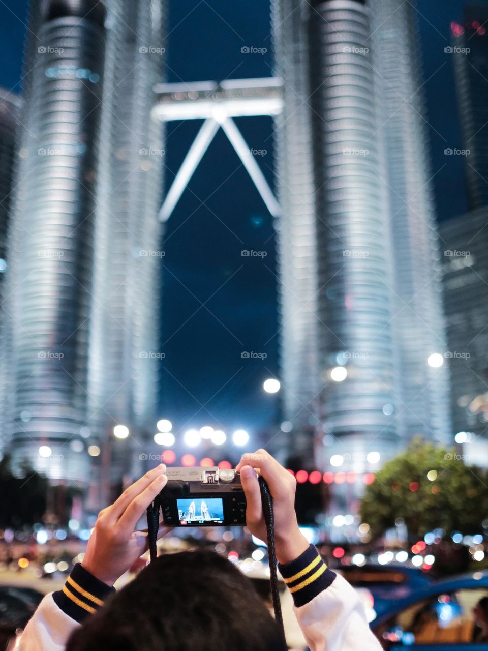 A tourist taking photo of the Petronas Towers at night