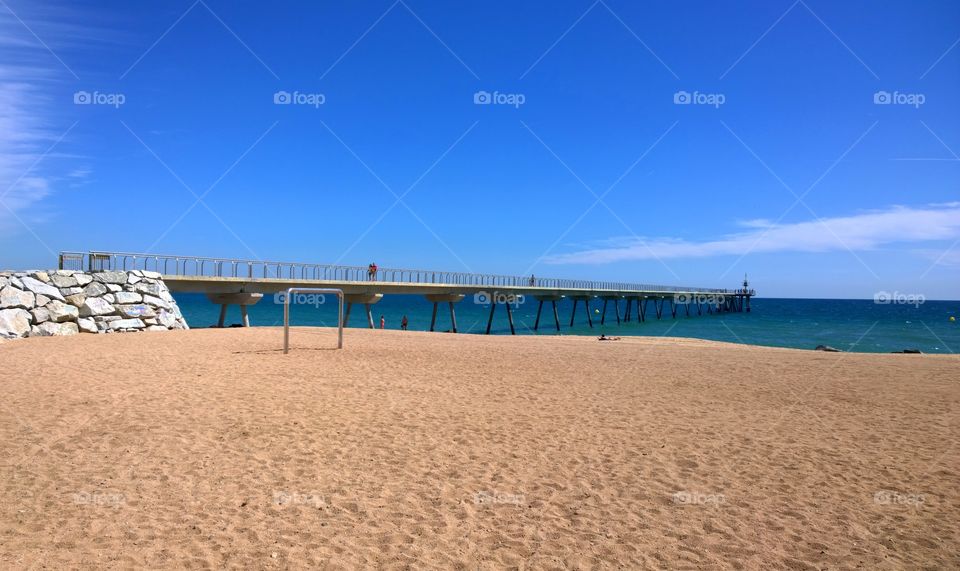 Beach in Badalona, Spain. View of Badalona beach and Pont del Petroli, a place for walking over the sea, in Badalona, Barcelona, Spain